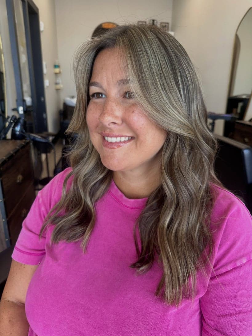Brightened beige-blonde money piece framing the face over a deeper base, with face-framing layers — hair by Alchemy Loft