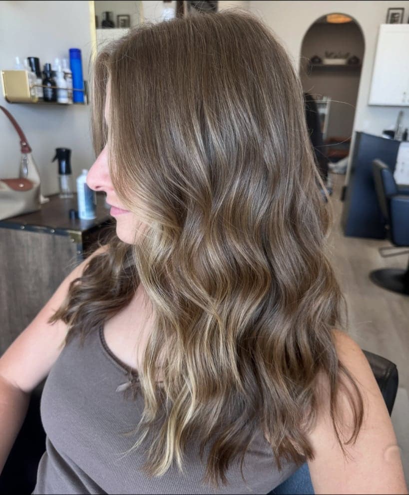 Soft brunette with subtle painted brightness toward the ends, side view — hair by Alchemy Loft