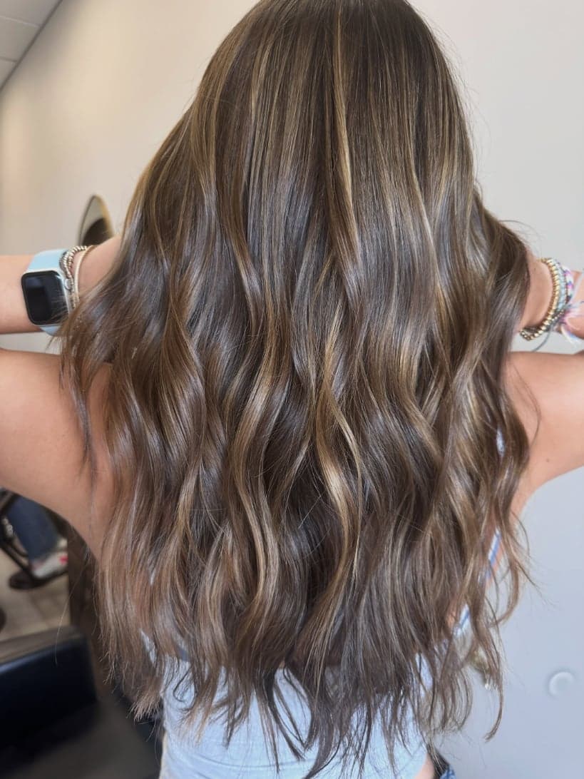 Long brunette waves with fine golden ribbons of dimension, back view — hair by Alchemy Loft