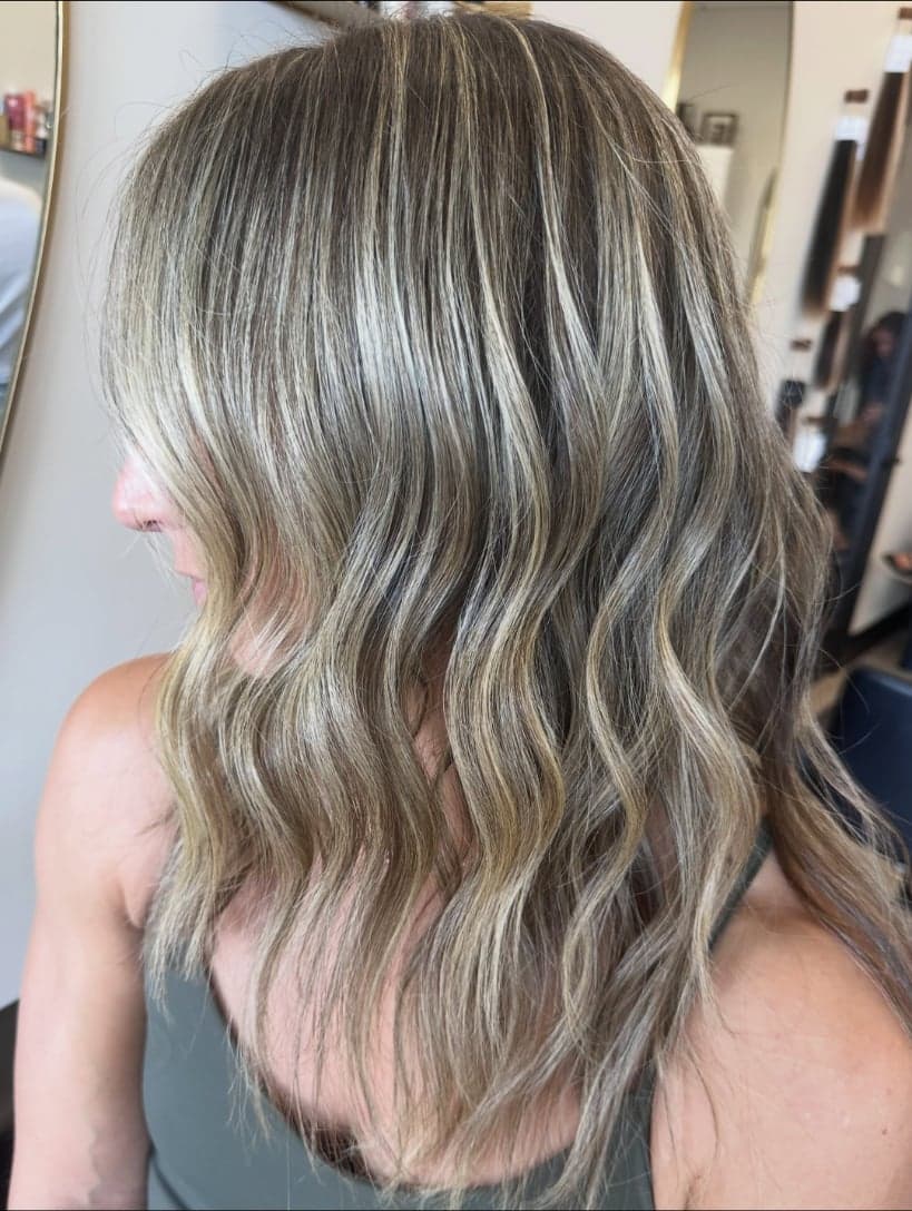 Close look at fine, cool blonde babylights woven through darker hair, side view — hair by Alchemy Loft