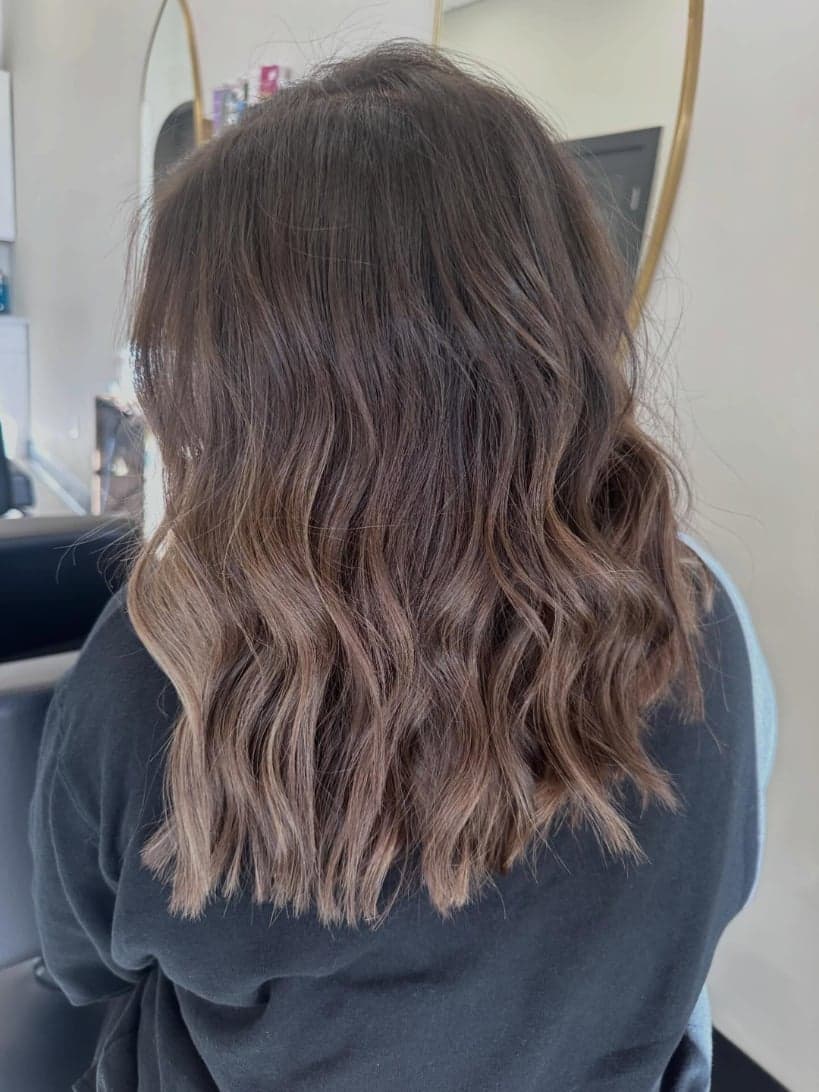 Soft, lived-in brunette balayage brightening toward the ends, back view — hair by Alchemy Loft