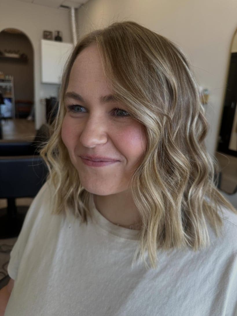 Soft blonde balayage on a wavy lob with brighter pieces around the face — hair by Alchemy Loft