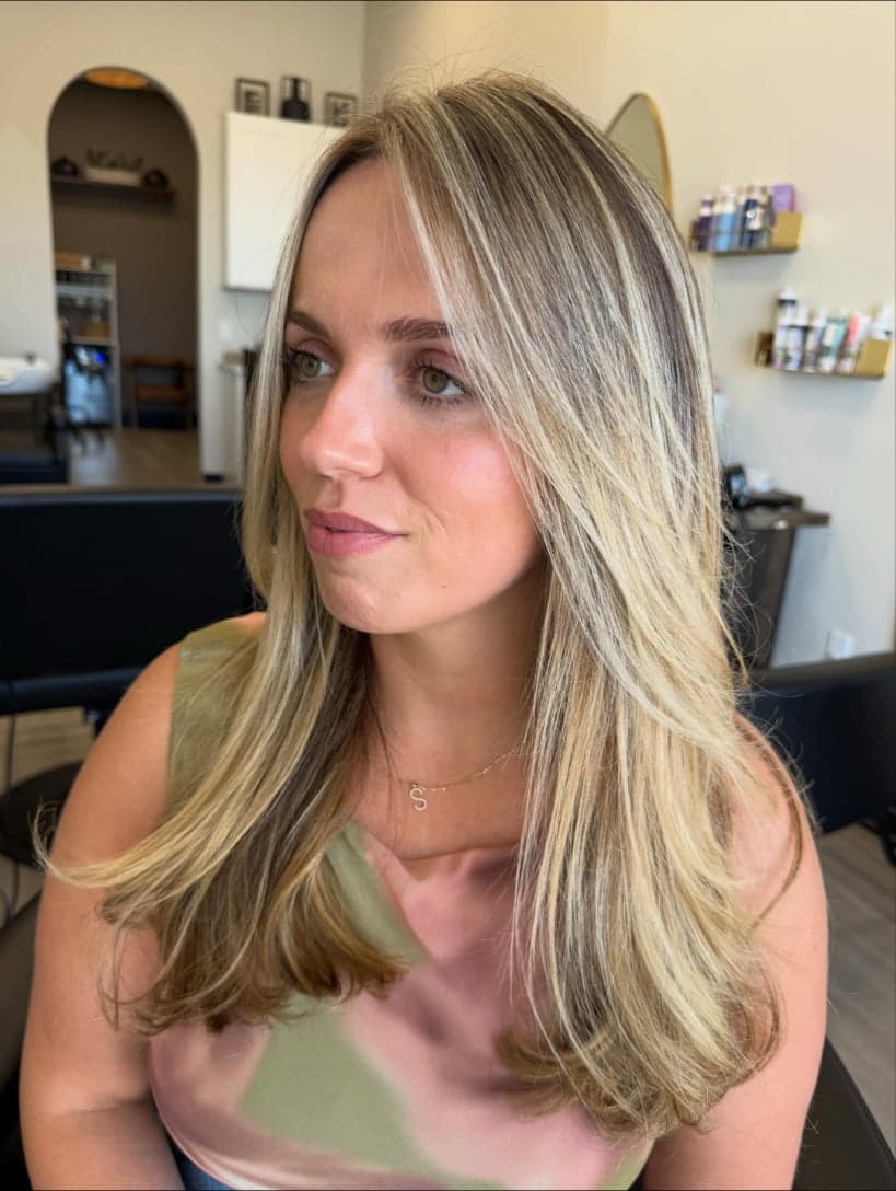 Bright blonde money piece framing the face, with long face-framing layers and dimensional blonde — hair by Alchemy Loft